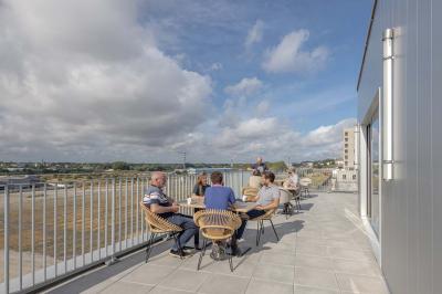 Terrasse moderne avec mobilier extérieur, vue sur une ville au coucher du soleil et ciel aux teintes orangées.