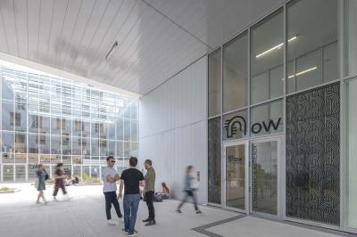 Terrasse moderne avec mobilier extérieur, vue sur une ville au coucher du soleil et ciel aux teintes orangées.