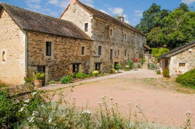 Vue d'un petit cours d'eau bordé de végétation luxuriante sous un ciel partiellement nuageux.