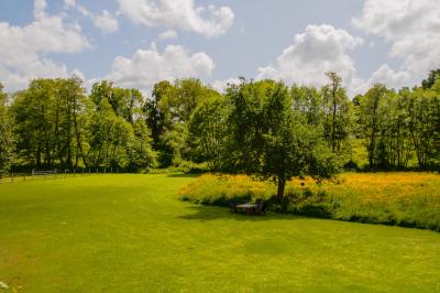 Vue d'un petit cours d'eau bordé de végétation luxuriante sous un ciel partiellement nuageux.