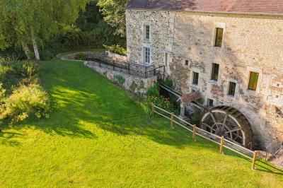 Vue d'un petit cours d'eau bordé de végétation luxuriante sous un ciel partiellement nuageux.