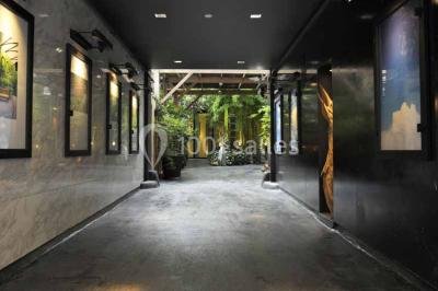 Salle lumineuse avec parquet, mobilier moderne, œuvres d'art au mur et grandes fenêtres laissant entrer la lumière naturelle.