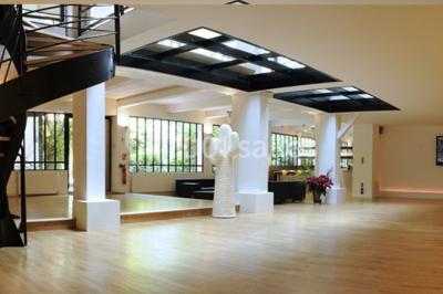 Salle lumineuse avec parquet, mobilier moderne, œuvres d'art au mur et grandes fenêtres laissant entrer la lumière naturelle.