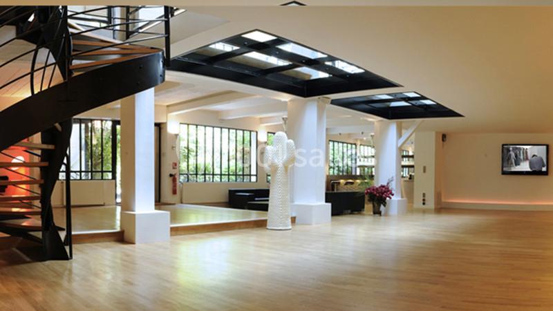 Intérieur spacieux et lumineux avec parquet, escalier en colimaçon, grandes fenêtres et décoration moderne.