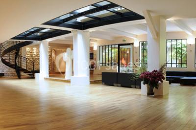 Salle lumineuse avec parquet, mobilier moderne, œuvres d'art au mur et grandes fenêtres laissant entrer la lumière naturelle.