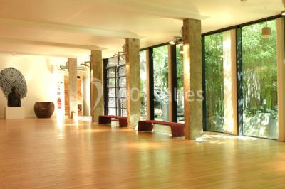 Salle lumineuse avec parquet, mobilier moderne, œuvres d'art au mur et grandes fenêtres laissant entrer la lumière naturelle.