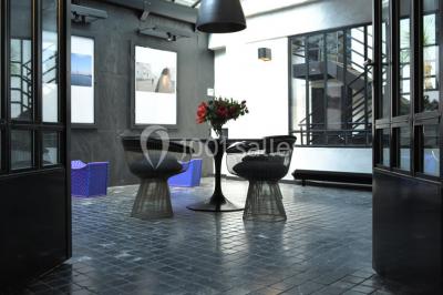 Salle lumineuse avec parquet, mobilier moderne, œuvres d'art au mur et grandes fenêtres laissant entrer la lumière naturelle.