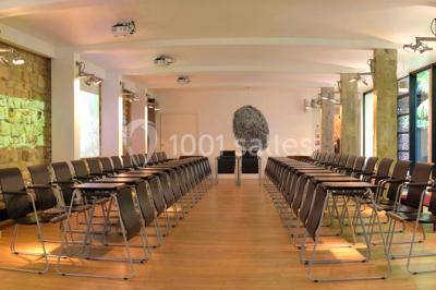 Salle lumineuse avec parquet, mobilier moderne, œuvres d'art au mur et grandes fenêtres laissant entrer la lumière naturelle.