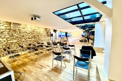 Salle lumineuse avec parquet, mobilier moderne, œuvres d'art au mur et grandes fenêtres laissant entrer la lumière naturelle.