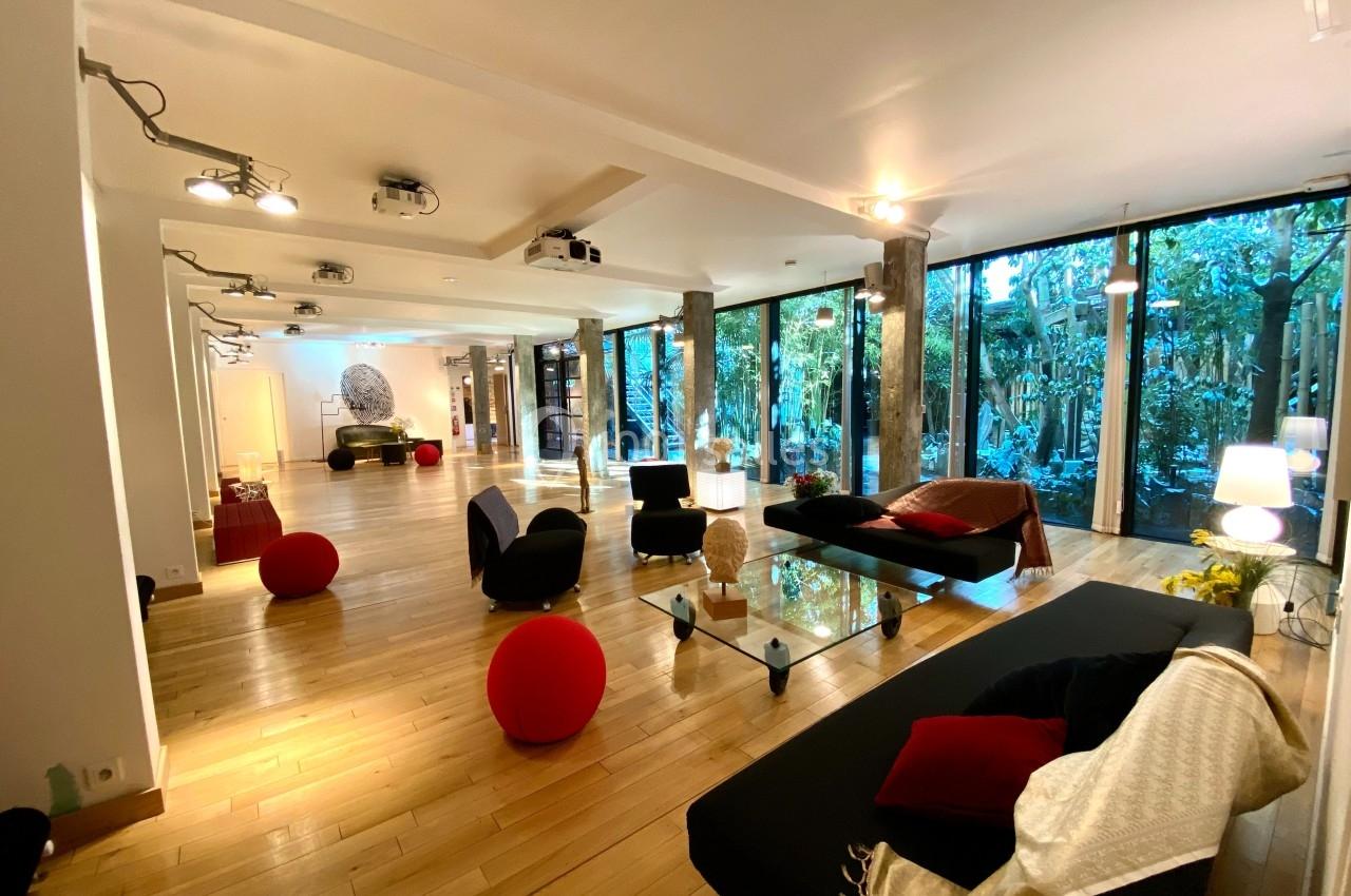 Salon spacieux et lumineux avec parquet en bois, mobilier moderne et grandes baies vitrées donnant sur un jardin.