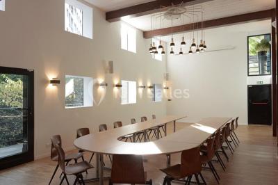 Salle lumineuse avec parquet, mobilier moderne, œuvres d'art au mur et grandes fenêtres laissant entrer la lumière naturelle.