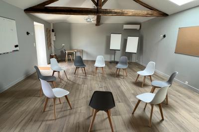 Cabane en forme de A éclairée de l'intérieur, entourée d'arbres dans un environnement nocturne.