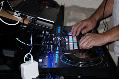 Table de mixage avec platines et boutons lumineux, accompagnée d'écrans affichant des interfaces de mixage audio.