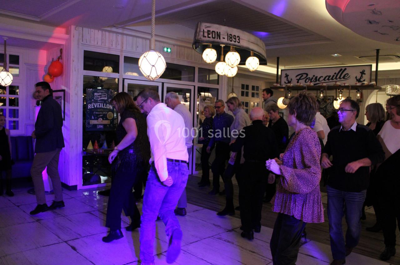 Des personnes dansent dans une salle éclairée avec des décorations maritimes et une ambiance festive.