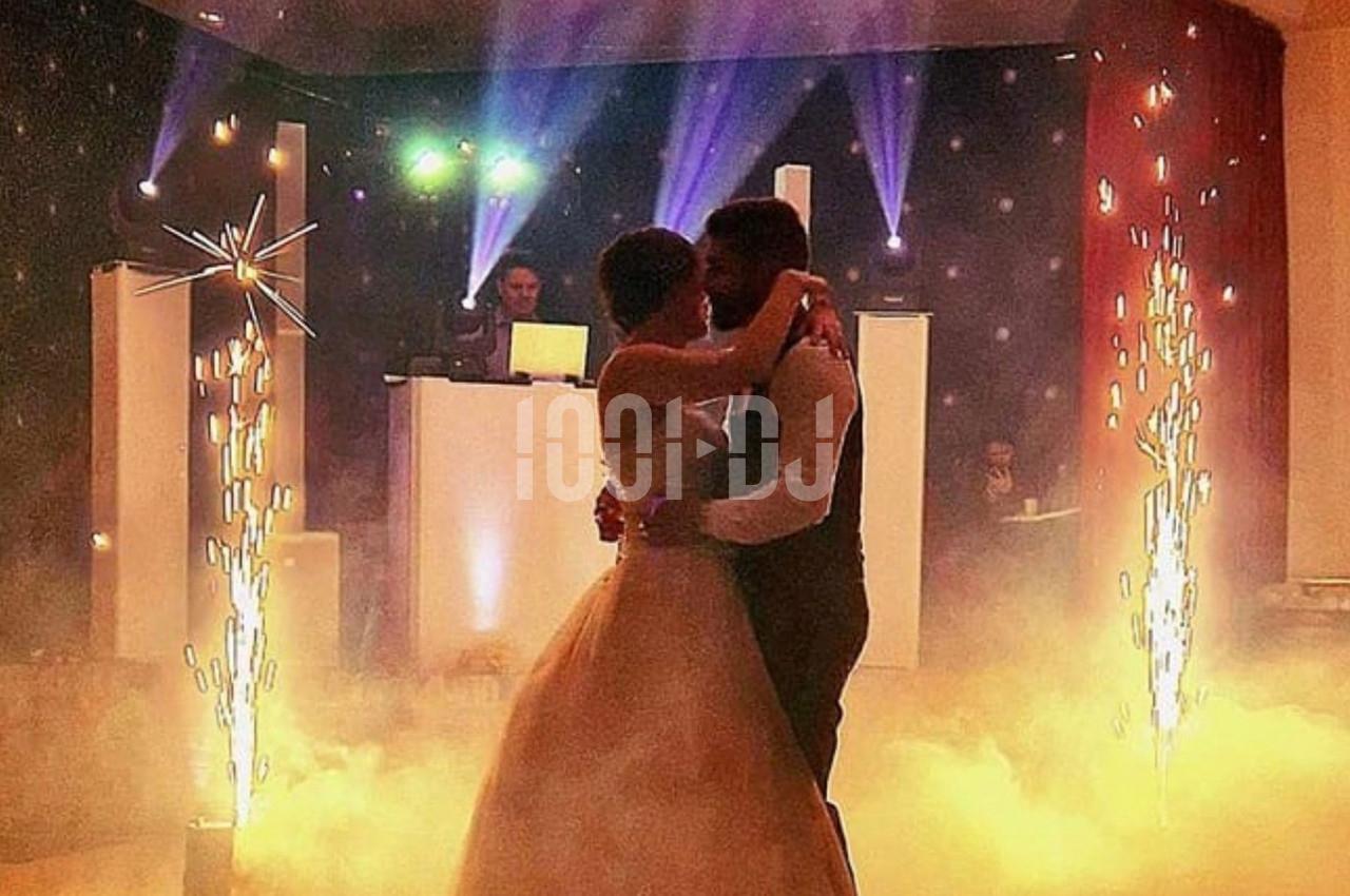 Un couple danse dans une ambiance festive avec éclairages colorés, fumée et étincelles décoratives.