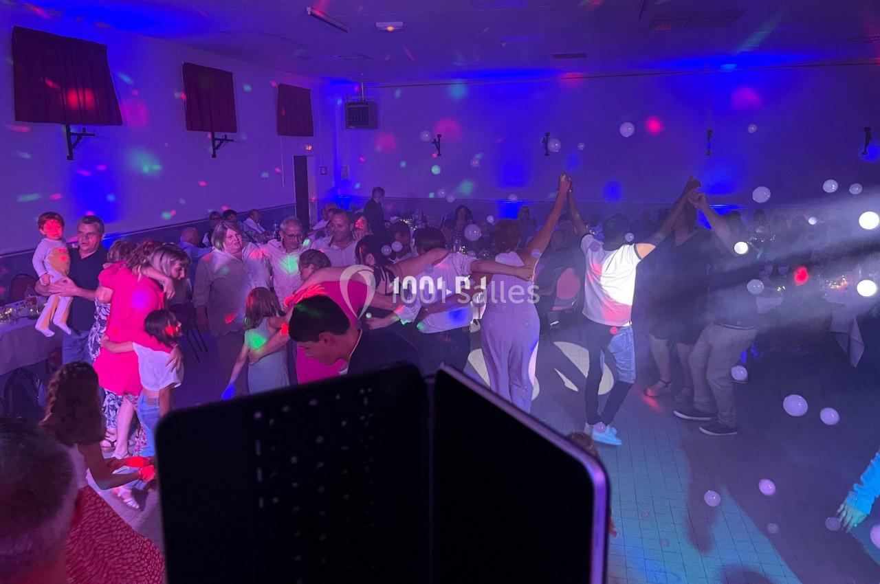 Groupe de personnes dansant dans une salle éclairée par des lumières colorées et des effets de fumée.