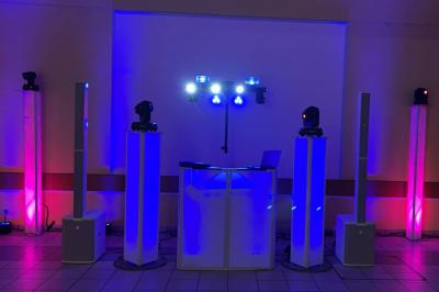 Un DJ mixe sur un ordinateur portable, entouré de lumières colorées dans un décor en bois avec des bouées suspendues.