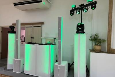 Un DJ mixe sur un ordinateur portable, entouré de lumières colorées dans un décor en bois avec des bouées suspendues.