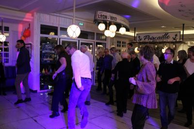 Un DJ mixe sur un ordinateur portable, entouré de lumières colorées dans un décor en bois avec des bouées suspendues.