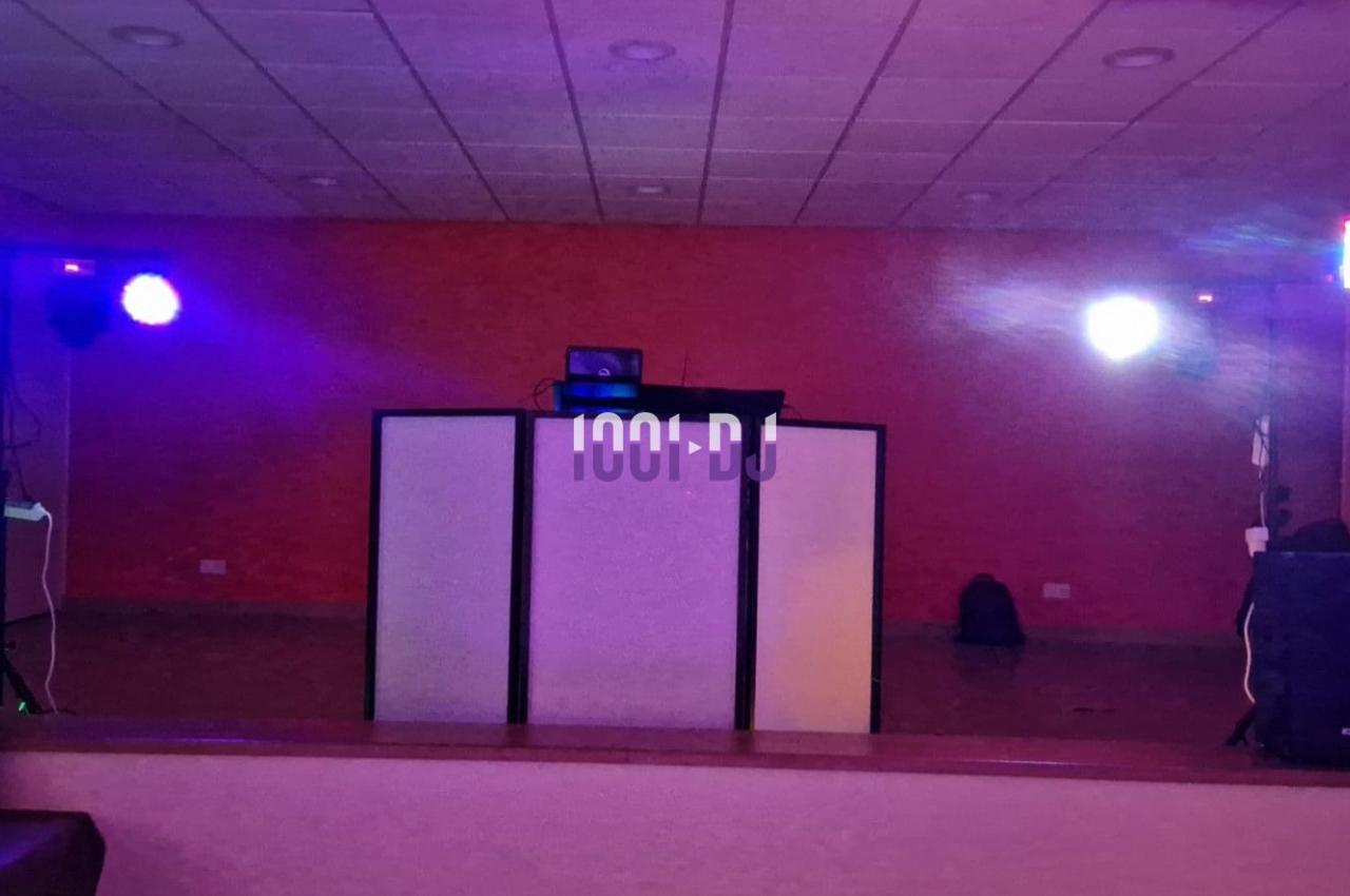 Installation de matériel de sonorisation et éclairage coloré dans une salle avec un fond de mur rouge.