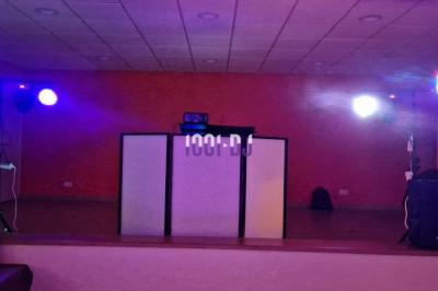 Installation de matériel de sonorisation et éclairage coloré dans une salle avec un fond de mur rouge.