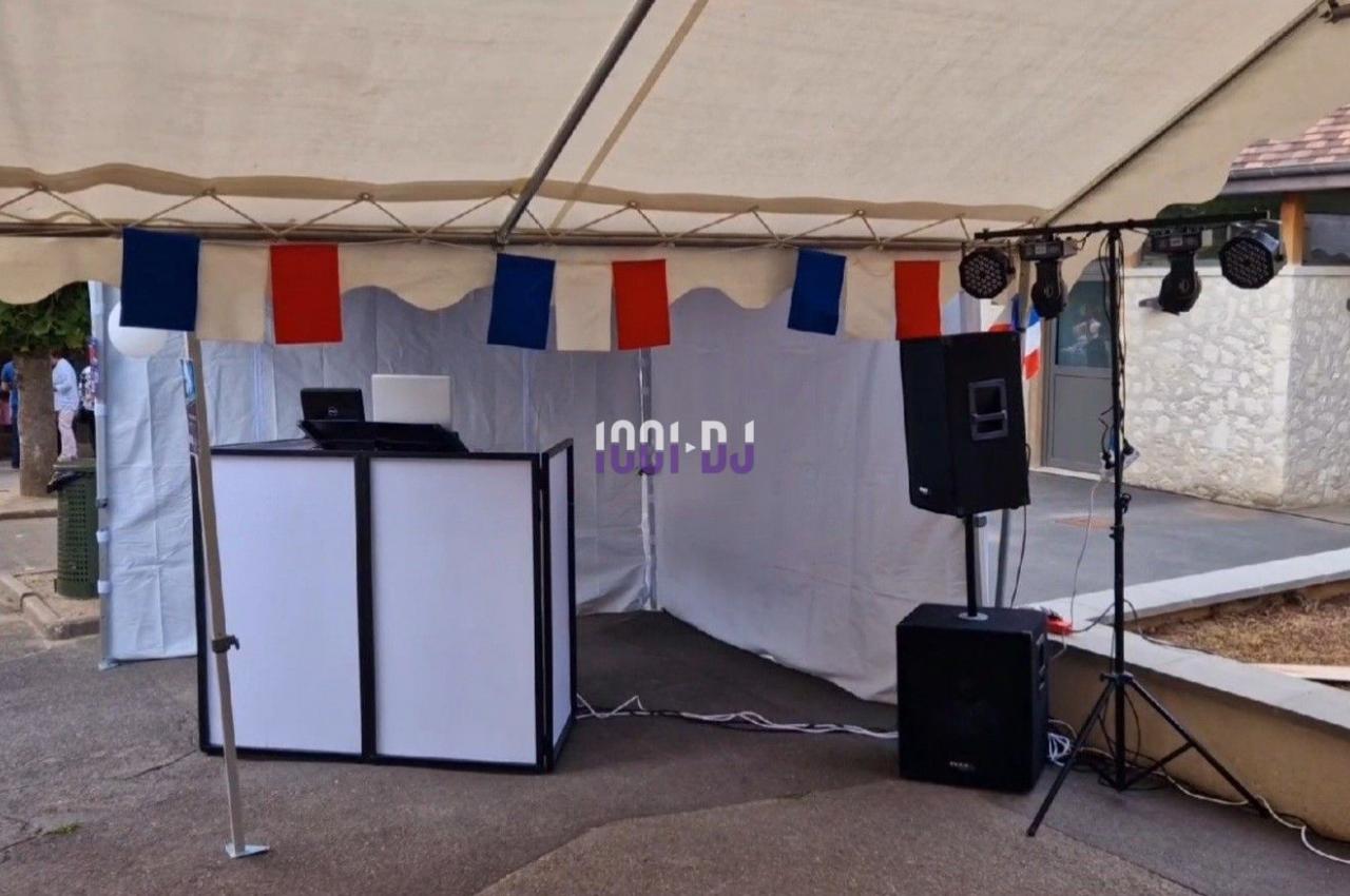 Stand de DJ sous une tente avec équipement audio et éclairage, décoré de drapeaux français.