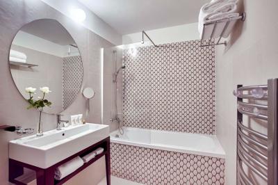 Escalier en marbre avec une rampe en bois, éclairé par des vitraux colorés et des appliques murales sur des murs rouges.