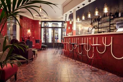 Escalier en marbre avec une rampe en bois, éclairé par des vitraux colorés et des appliques murales sur des murs rouges.