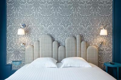 Escalier en marbre avec une rampe en bois, éclairé par des vitraux colorés et des appliques murales sur des murs rouges.