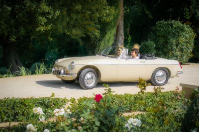 Voiture décapotable rouge garée dans un champ de lavande sous un ciel dégagé.