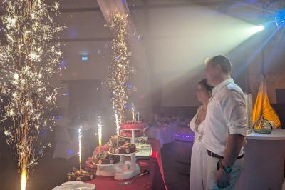 Salle de réception décorée avec des tables rondes, nappes blanches, chaises transparentes et guirlandes lumineuses.