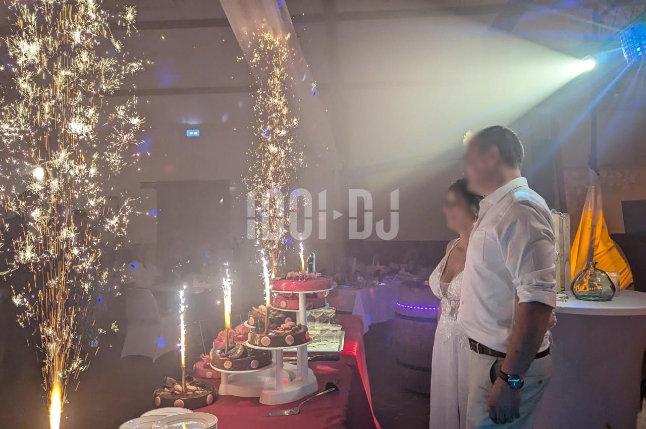 Un couple debout près d'une table décorée avec des desserts et des fontaines lumineuses dans une salle de réception.