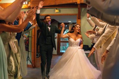 Salle de réception décorée avec des tables rondes, nappes blanches, chaises transparentes et guirlandes lumineuses.