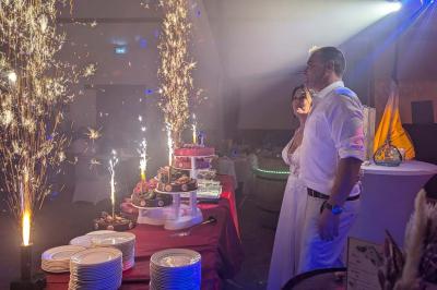 Salle de réception décorée avec des tables rondes, nappes blanches, chaises transparentes et guirlandes lumineuses.