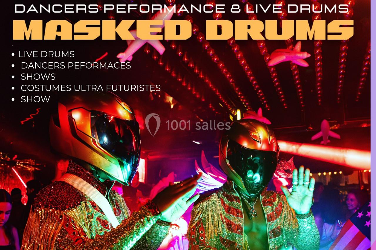 Deux artistes en costumes futuristes et casques brillants jouent de la musique dans une ambiance festive et lumineuse.