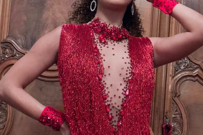 Personne portant un costume élaboré avec des ailes et un masque argenté, dans un décor intérieur faiblement éclairé.