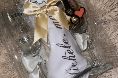 Miniature Miss Majestic #22 Flûte personnalisée avec le prénom ’Marion’ et bougie marquée ’50 ans’, posées sur une table devant un fond rose.