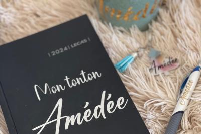 Miniature Miss Majestic #24 Flûte personnalisée avec le prénom ’Marion’ et bougie marquée ’50 ans’, posées sur une table devant un fond rose.