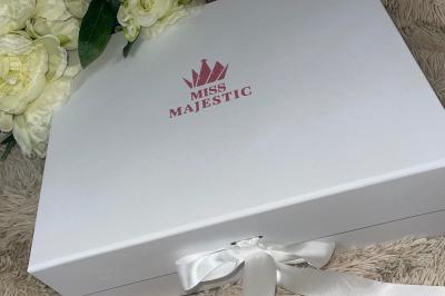 Miniature Miss Majestic #32 Flûte personnalisée avec le prénom ’Marion’ et bougie marquée ’50 ans’, posées sur une table devant un fond rose.