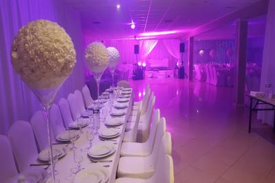 Plusieurs personnes discutent devant un bâtiment avec des voitures garées, dont une voiture rouge sportive.