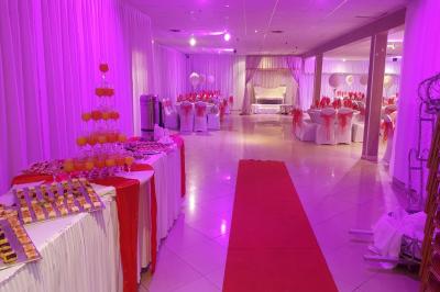 Plusieurs personnes discutent devant un bâtiment avec des voitures garées, dont une voiture rouge sportive.