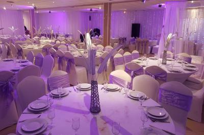 Plusieurs personnes discutent devant un bâtiment avec des voitures garées, dont une voiture rouge sportive.