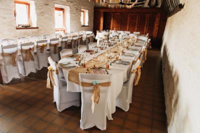 Ballon arc-en-ciel en forme de chiffre un, table décorée avec nappe rouge et bouteille au premier plan.