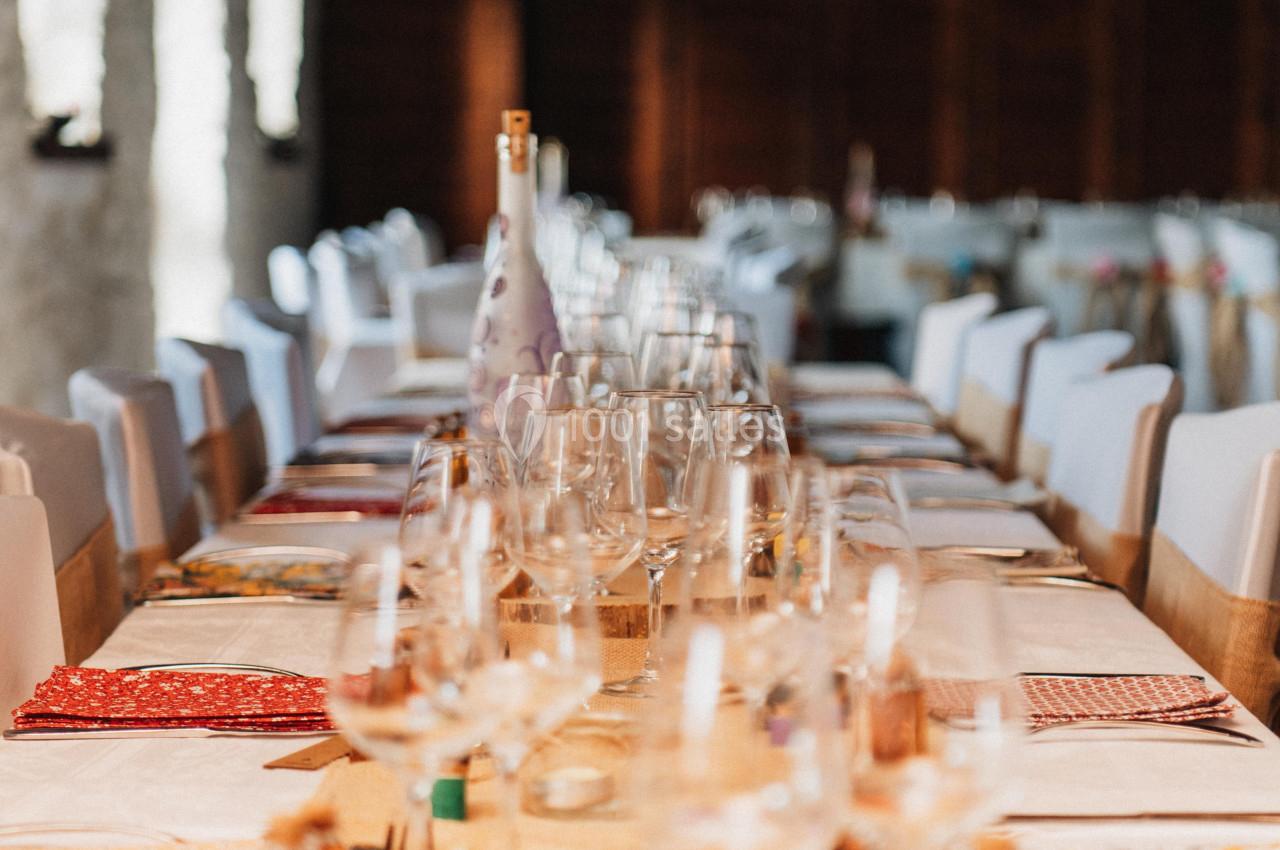 Table décorée pour un repas festif, avec nappes colorées, verres et guirlandes suspendues dans une salle lumineuse.