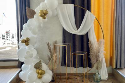 Décoration d'anniversaire avec ballons violets et blancs, chiffre lumineux ’18’ et présentoirs cylindriques blancs.