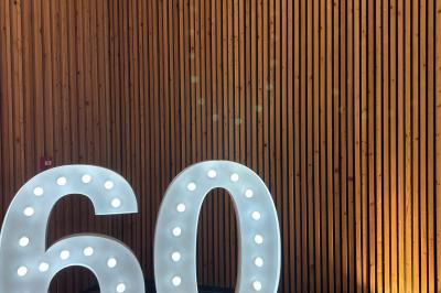 Décoration d'anniversaire avec ballons violets et blancs, chiffre lumineux ’18’ et présentoirs cylindriques blancs.