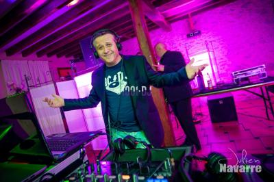 Un homme en costume utilise une table de mixage lors d'un événement en extérieur, avec des ballons en arrière-plan.