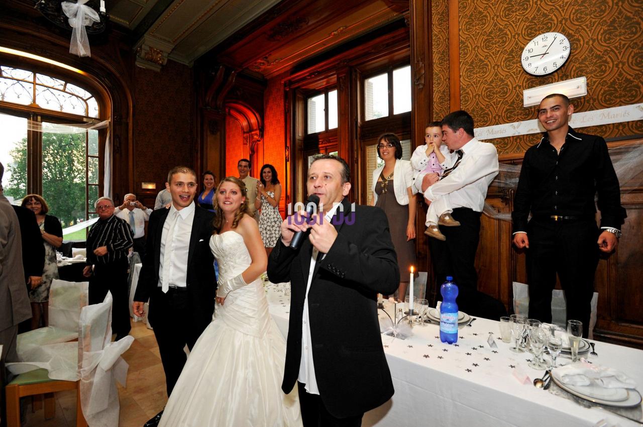 Un groupe de personnes lors d'une réception de mariage dans une salle élégante avec des fenêtres et des boiseries.