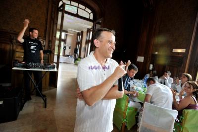 Un homme en costume utilise une table de mixage lors d'un événement en extérieur, avec des ballons en arrière-plan.