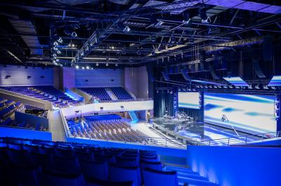 Miniature Location salle Croissy-Beaubourg (Seine-et-Marne) - La Mega Place #3 Vue aérienne d'un grand bâtiment moderne avec un parking rempli de voitures à l'avant et des arbres en arrière-plan.